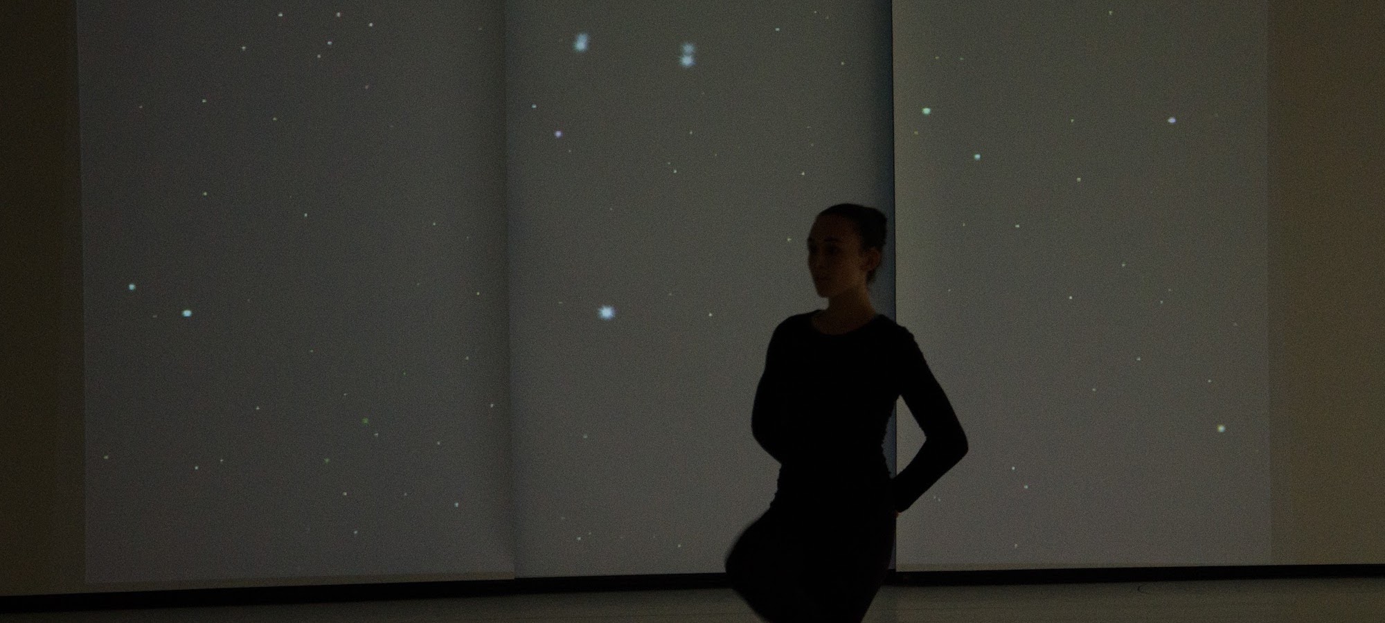 A dancer silhouetted in front of a projection of stars